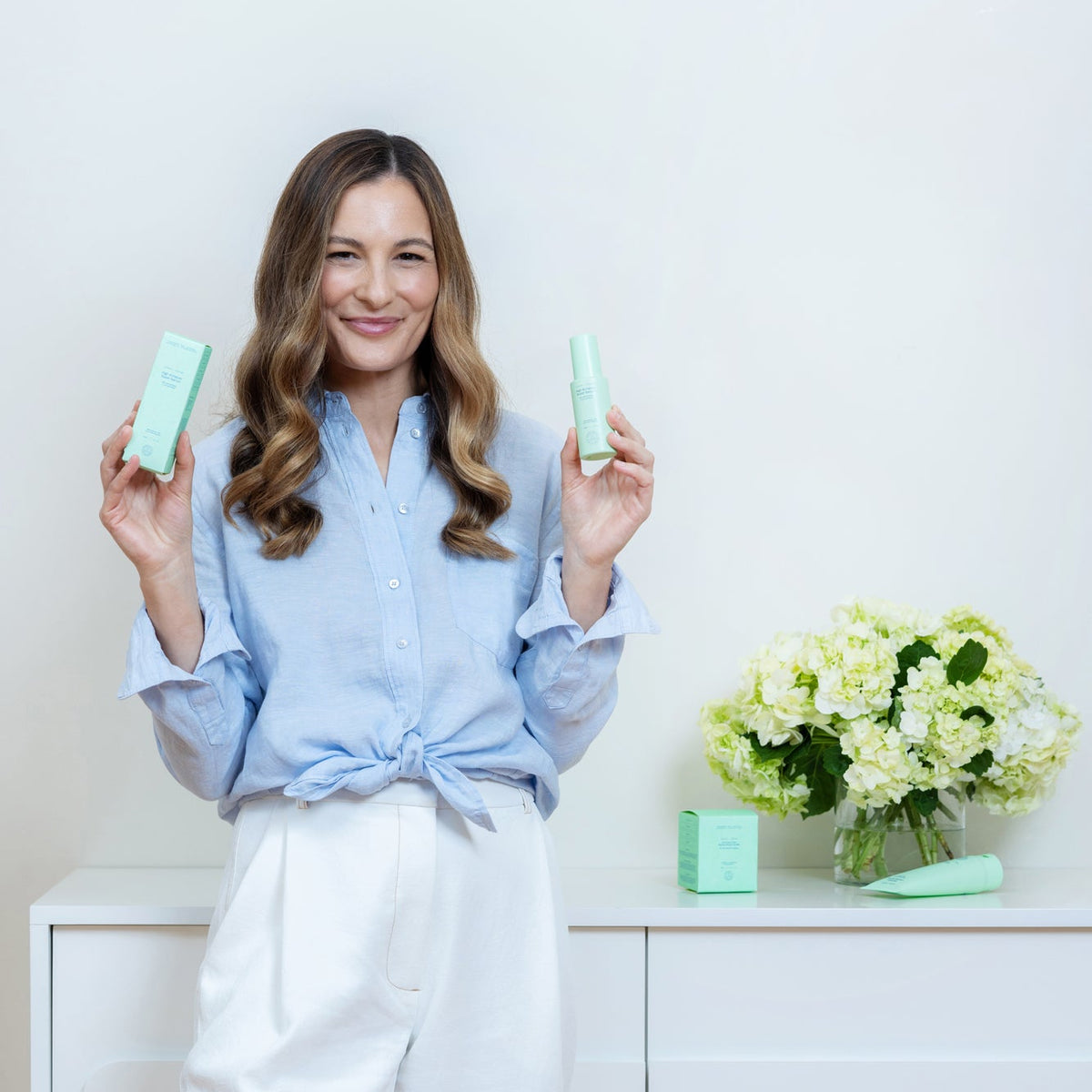 Jade Williams, founder of SKINPOSSIBLE, holding the cleanser and the barrier repair serum