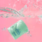 Barrier Repair Soufflé jar submerged in water against a pink background, with bubbles and splash around it